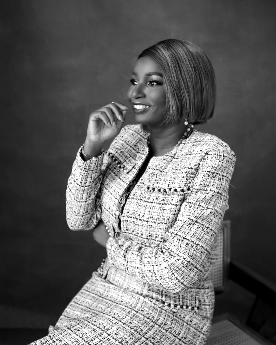 Bolanle smiling, seated in a tweed suit
